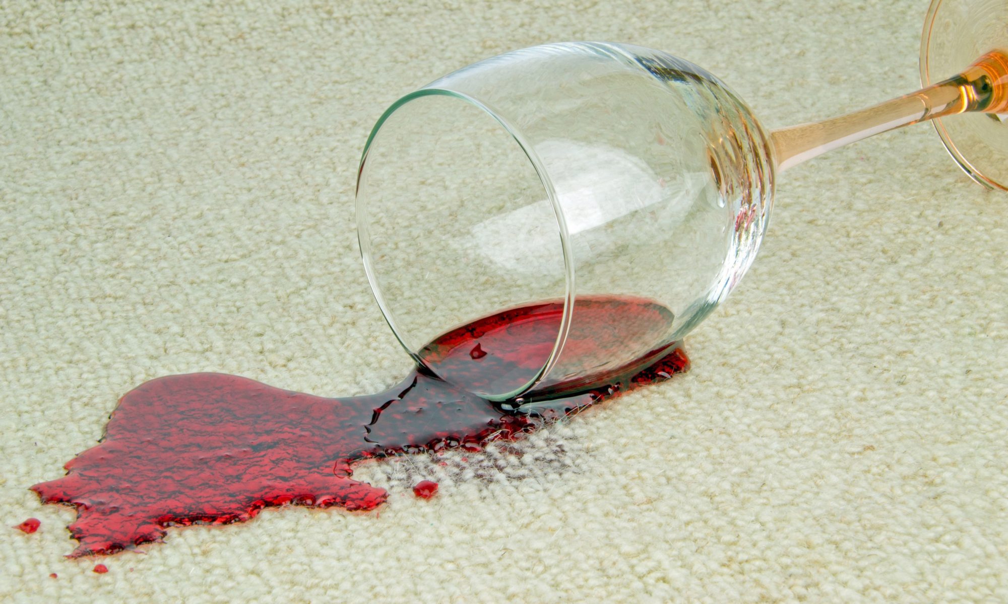 a glass of red wine spilled onto a white carpet